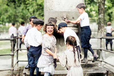 Kids around a fountain in 1911 to get water on a hot day